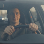 Jonge bestuurder met handen aan het stuur in druk verkeer, opfriscursus om weer met vertrouwen te rijden