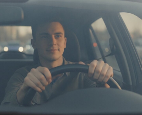Jonge bestuurder met handen aan het stuur in druk verkeer, opfriscursus om weer met vertrouwen te rijden