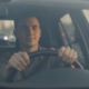 Jonge bestuurder met handen aan het stuur in druk verkeer, opfriscursus om weer met vertrouwen te rijden