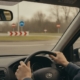 Jonge bestuurder met handen aan het stuur die een rotonde nadert