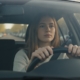 Jonge vrouw haalt rustig adem achter het stuur van de lesauto voor haar faalangstexamen bij het CBR