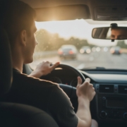 Jonge bestuurder met beide handen aan het stuur tijdens een lange vakantierit in de zomer