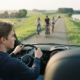 Jonge bestuurder rijdt langzaam op een smalle dijkweg en passeert fietsers