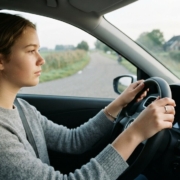 Leerling met beide handen aan het stuur op een rustige weg tijdens de rijles