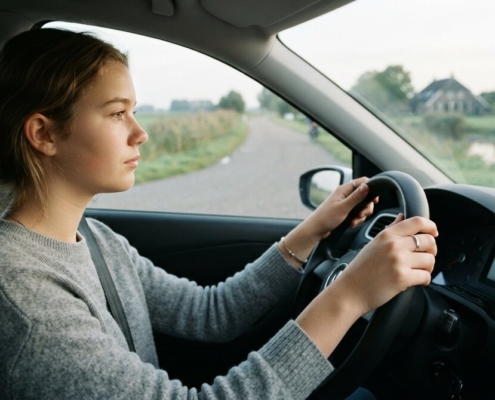 Leerling met beide handen aan het stuur op een rustige weg tijdens de rijles