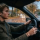 Jonge bestuurder rijdt in de herfst over een weg vol natte bladeren in de schemering
