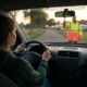 Jonge bestuurder stopt voor een verkeersregelaar met opgeheven hand bij een evenement